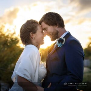 Gros plan d'un couple de mariés front contre front dans la lumière chaude du soleil couchant.
