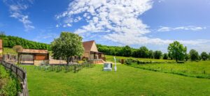 Large plan d'un domaine de mariage avec une batisse en pierre, une pelouse verte et des chaises disposees pour une ceremonie exterieure.