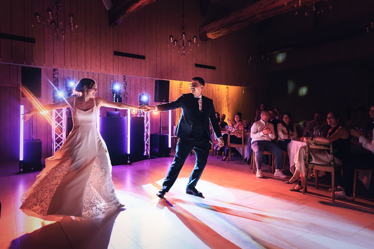 Camille et Paul dansent sur la piste de danse éclairée par des faisceaux lumineux violets.