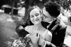 Gros plan en noir et blanc du marié embrassant la joue de la mariée qui ferme les yeux de bonheur.