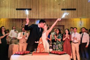 Les mariés Camille et Paul s'embrassent devant leur pièce montée en choux avec des cierges magiques dans la salle de réception du Château des Broyers.