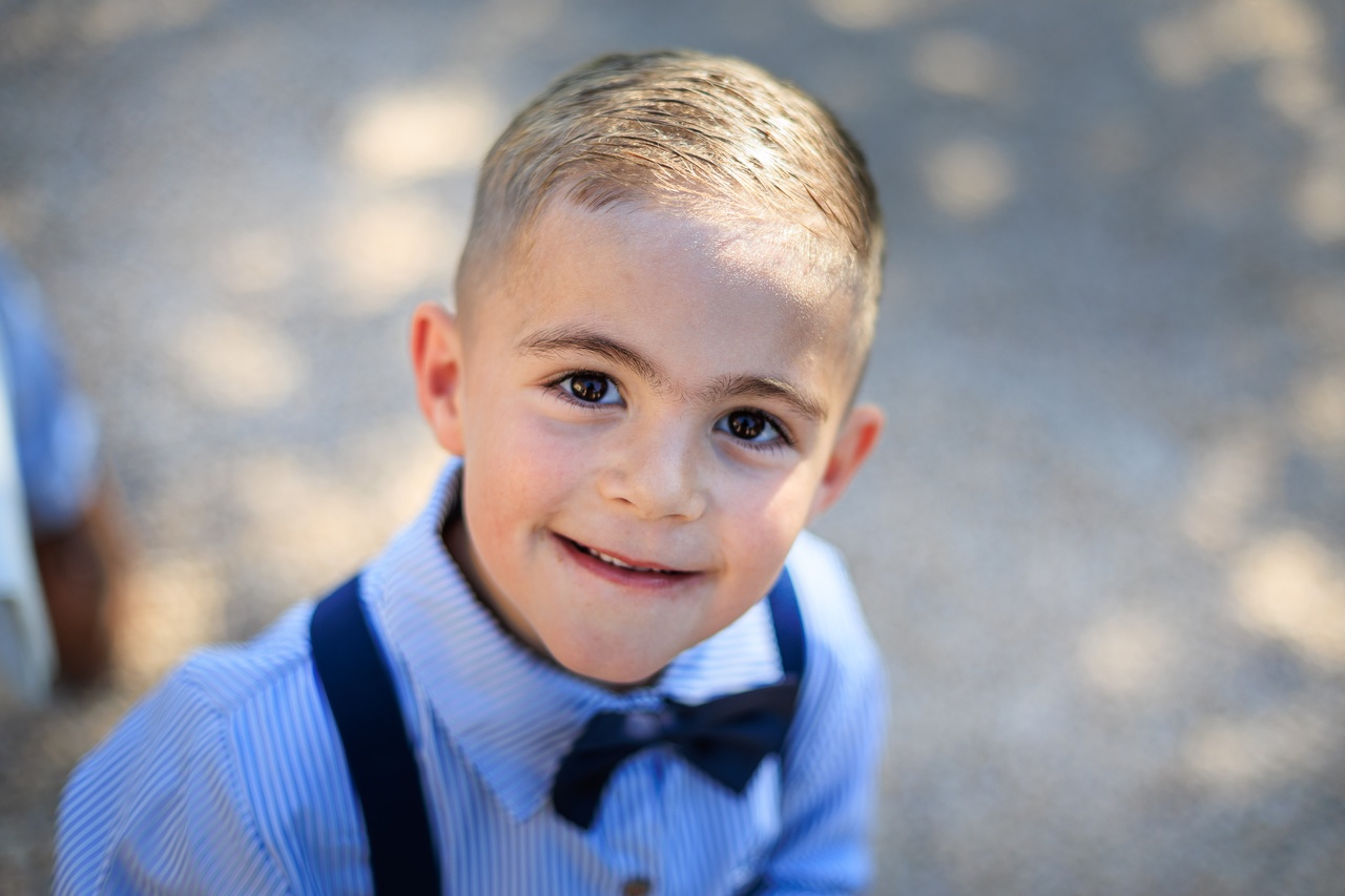Portrait rapproche d'un petit garcon souriant portant une chemise a rayures bleues et un noeud papillon noir.