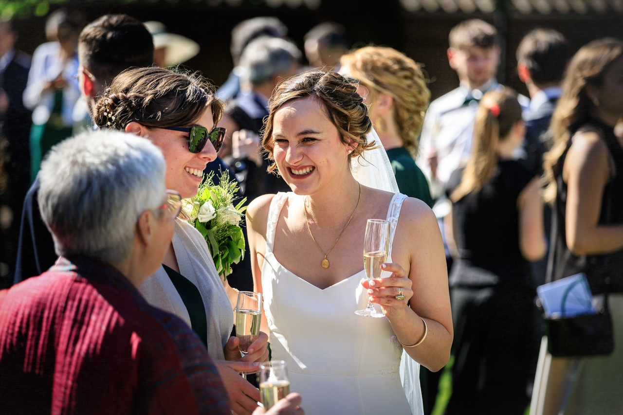 La mariée Camille rit aux éclats avec ses amies lors du cocktail en extérieur.