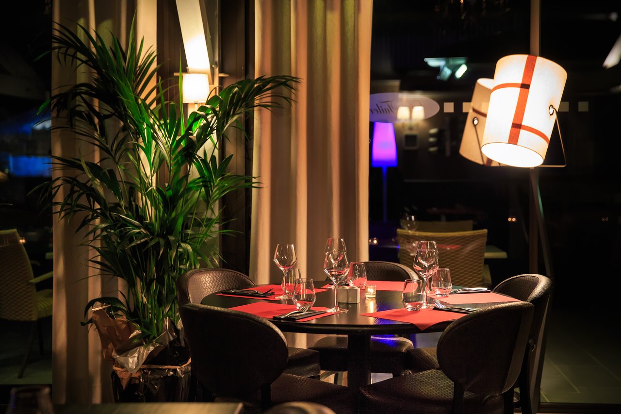 Table dressée avec verres et couverts dans un restaurant élégant, éclairé par des lampes modernes — photographie immobilière à Mâcon