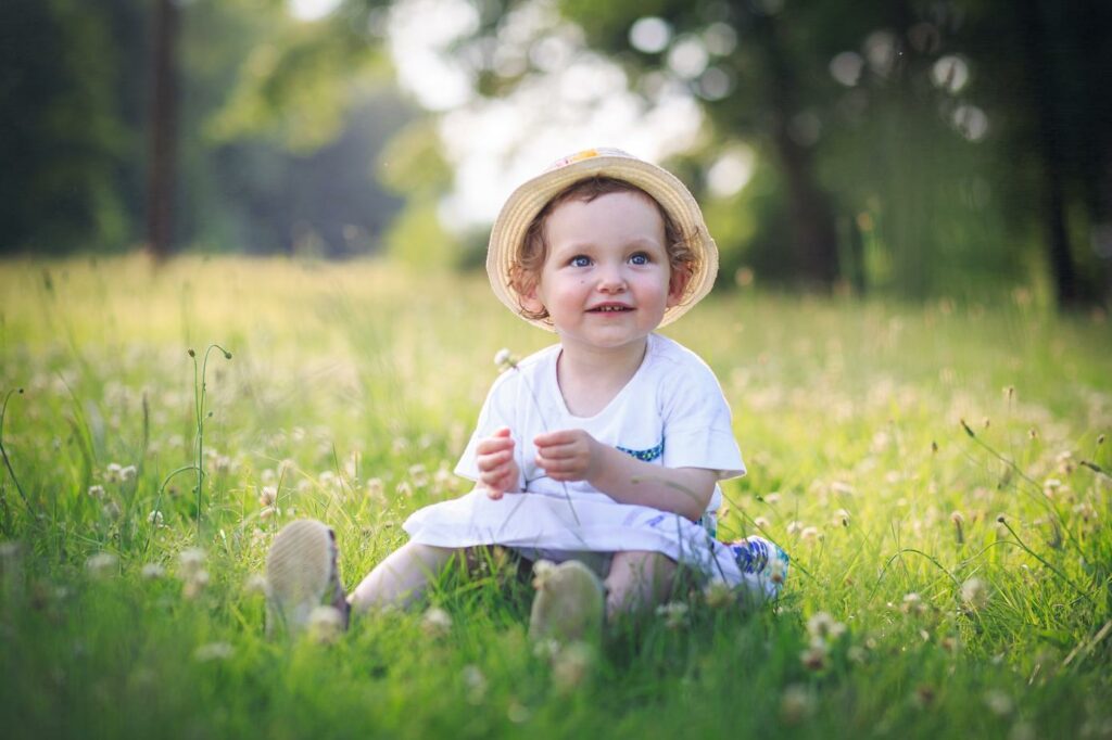 Enfant en chapeau de paille assis dans un champ de fleurs — photographe de famille à Villefranche-sur-Saône