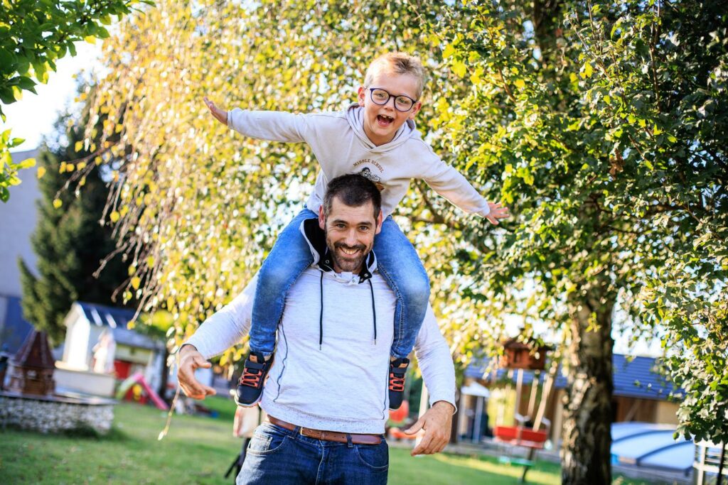Père portant son fils sur les épaules, bras écartés — photographe de famille à Paray-le-Monial