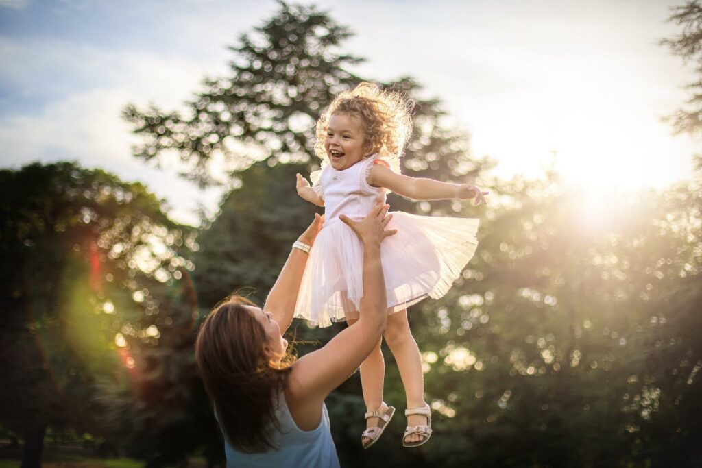 Maman faisant s'envoler sa petite fille en riant — photographe de famille à Paray-le-Monial