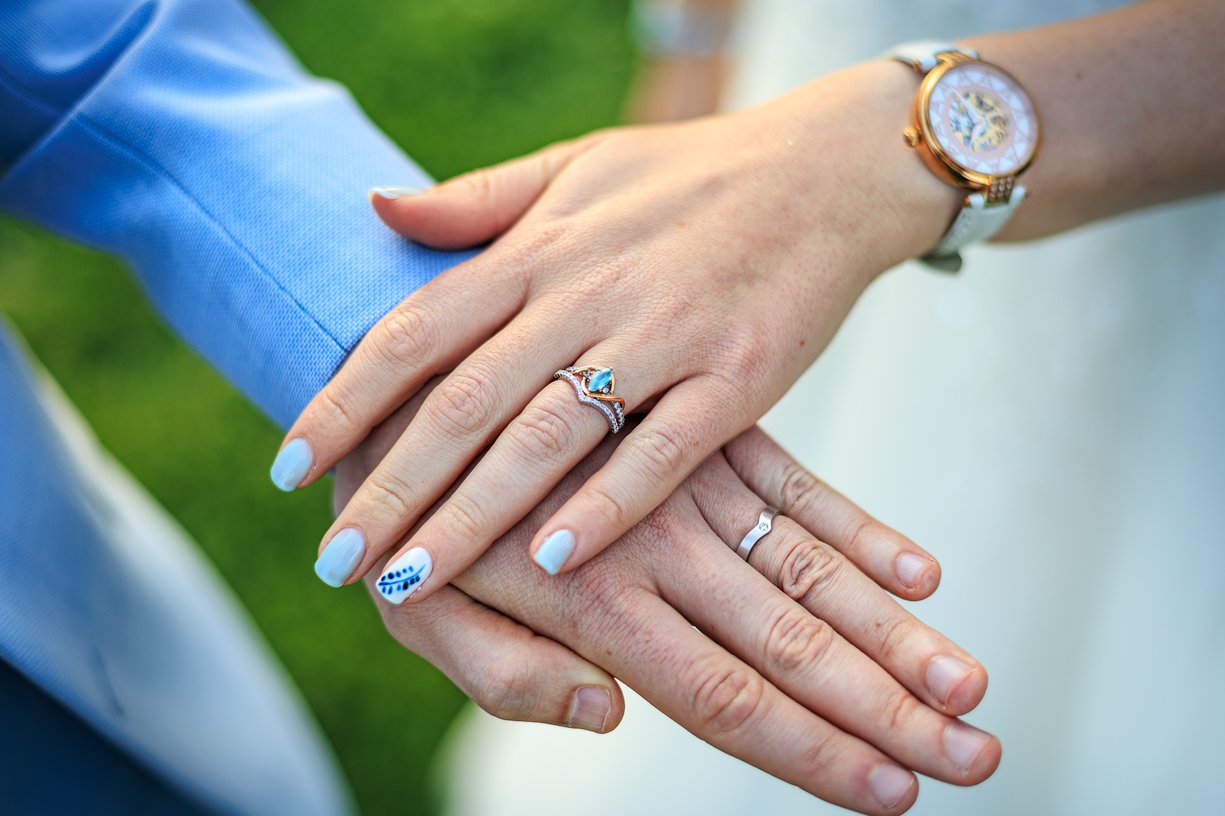 Les deux alliances sur les mains posees d'Amandine et Vincent, montre au poignet