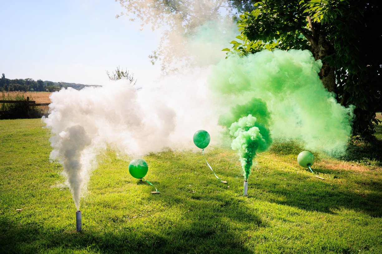 Fumigenes verts et ballons dans l'herbe a la fin de la ceremonie laique a la Ferme du Tremblay