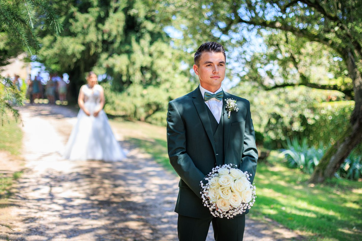 Dimitri attend sur le chemin, bouquet a la main, Camille en robe floue au loin qui approche