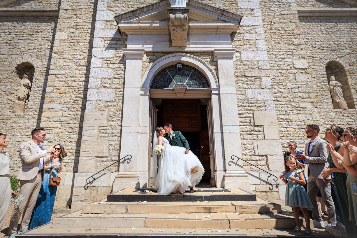 Dimitri embrasse Camille cambree sur le parvis de l'eglise de Feillens, invites applaudissant de chaque cote
